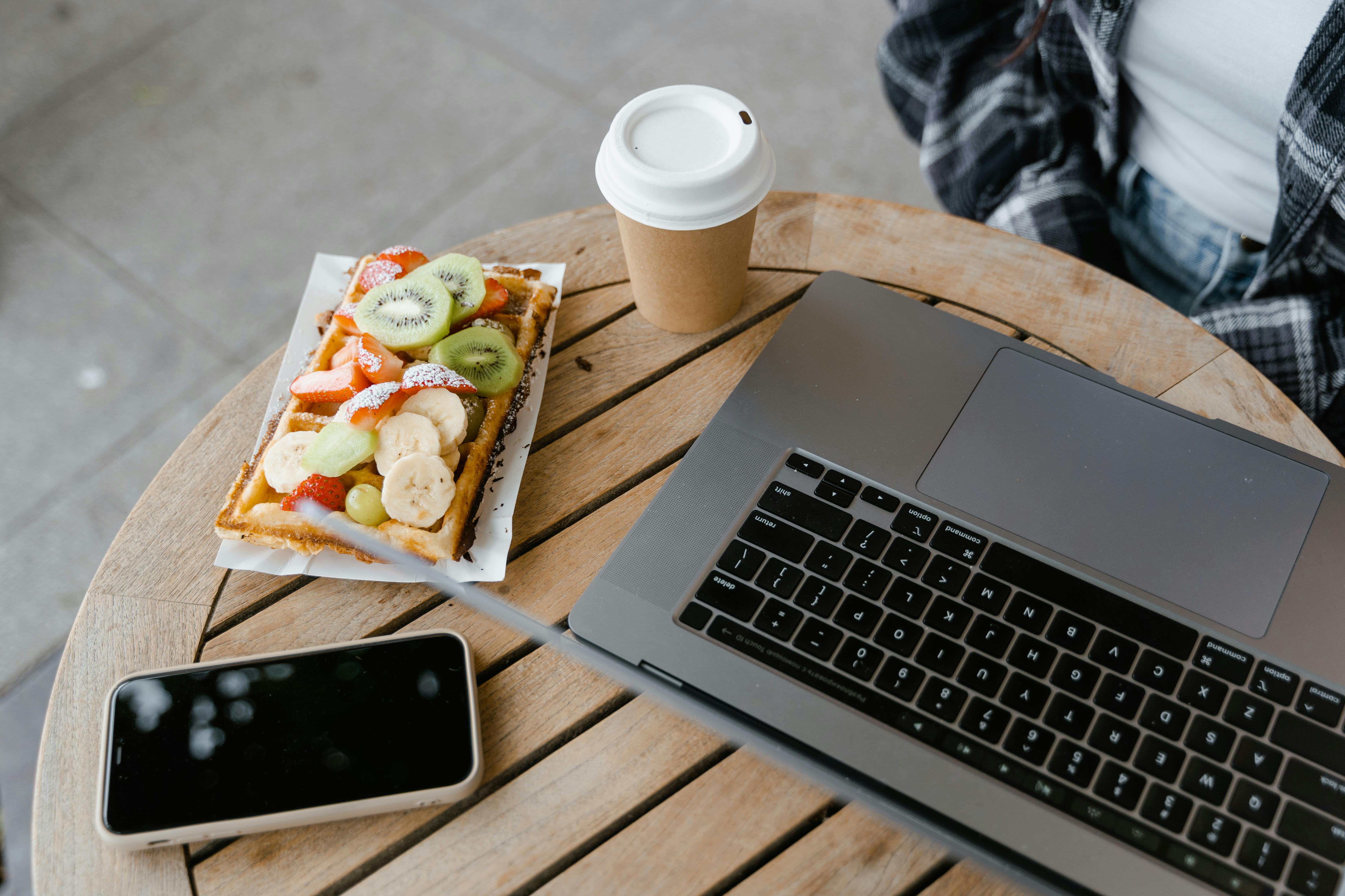 Cozy cafe scene with a waffle, coffee, and a laptop. Perfect for remote work lifestyle.